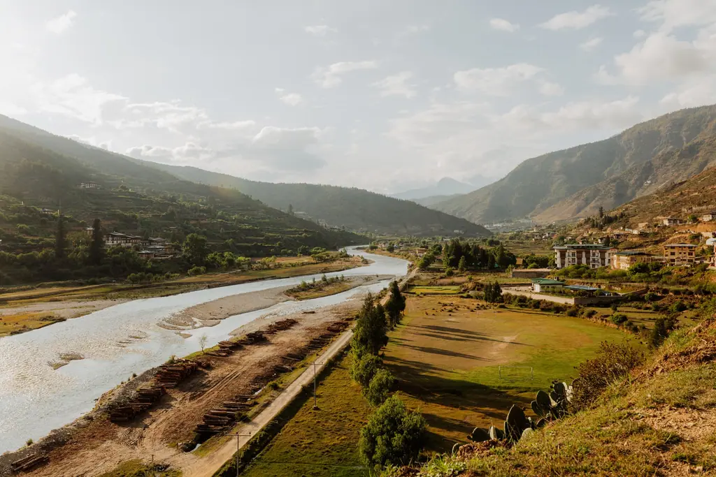 A braided river winding through a valley of green fields and terraced slopes