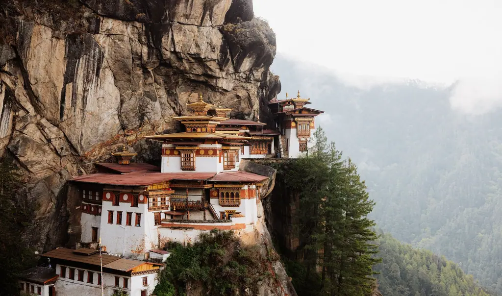 Paro Taktsang, the Tiger's Nest monastery, clinging to a sheer granite cliff above forested slopes